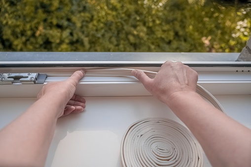 Installation of weatherproof insulation. worker sticking sealing foam tape on indoor window