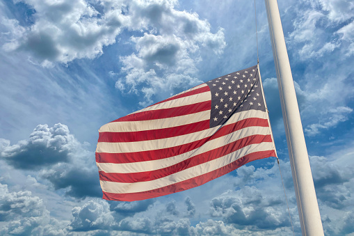 A group of United States of flags at half mast.  The position of a flag which is being flown some way below the top of its staff as a mark of respect for a person who has died.