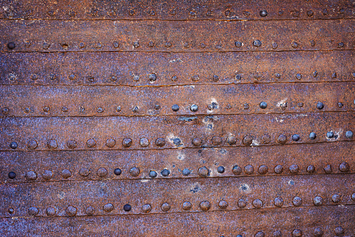 Weathered rusty metal textured background with big rivets