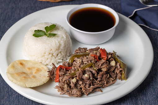 Shredded meat with rice, typical Cuban food on white plate.