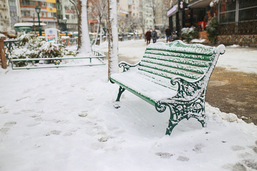 Winter park with benches covered with snow in the evening. Winter evening in a central park.