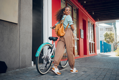 Happy, city and girl with a bicycle to travel to school, university or college to reduce carbon footprint outdoors. Smile, street and young student traveling or riding a cool bike in an urban town