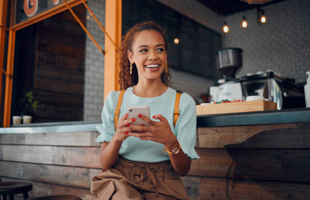 teléfono, redes sociales y cafetería con una clienta pensando en una idea mientras está sentada en un mostrador en un café. móvil, internet y comunicación con una joven sentada en un restaurante - restaurant sitting adult beauty fotografías e imágenes de stock