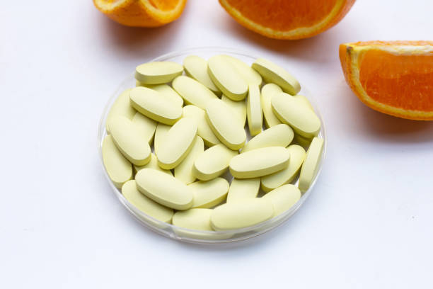 istock Vitamin c pills with orange fruit on white background. 1449138497