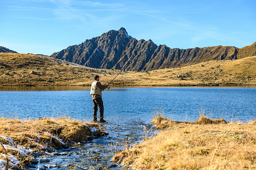Fisherman fishing in a beautiful lake in the mountains