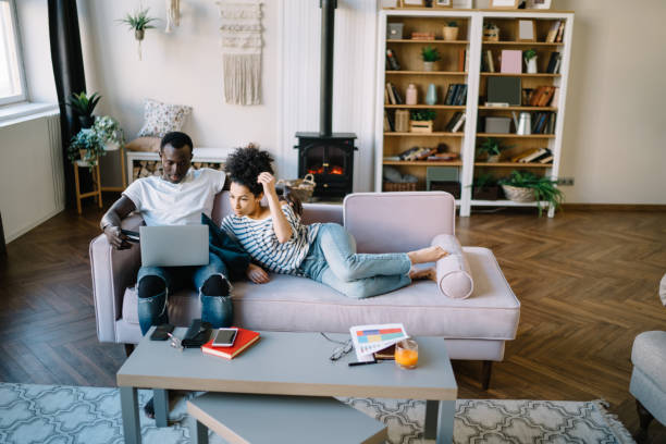 istock Multiracial couple placing in sofa with credit card and browsing laptop 1449142414