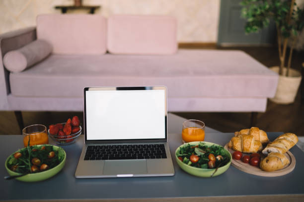 istock Laptop next to food and drinks on coffee table in room 1449142437