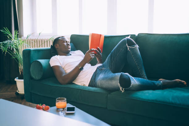 istock Smart black man enjoying reading book in living room 1449142497