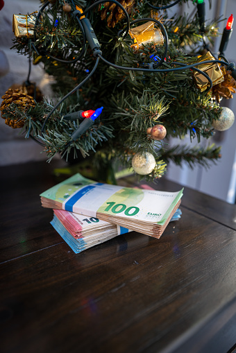under a christmas tree lies a bundle of cash