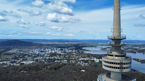 A bird's eye view shot of a Telstra Tower in Canberra with a background of a cityscape