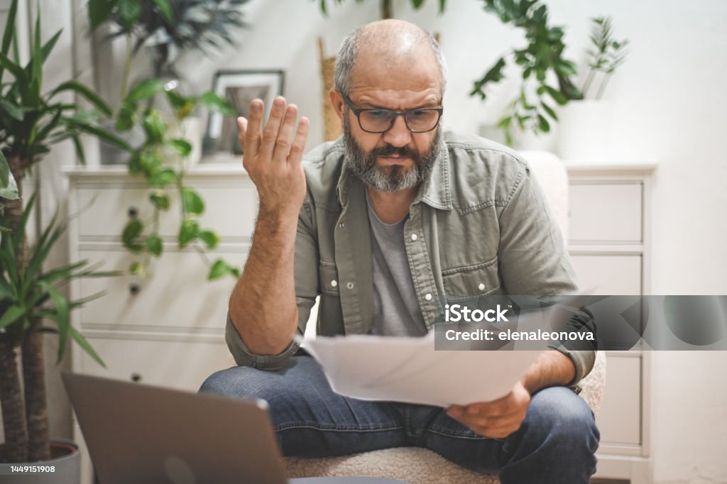 Mature man working from home Paycheck Stock Photo