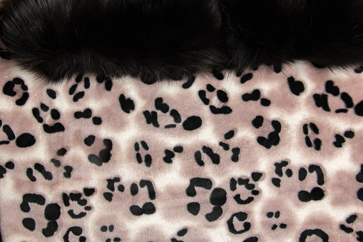 Close-up pattern of fleece fabric with leopard pattern. Brown-beige and black striped repeating on the surface of fur clothes, abstract texture background.