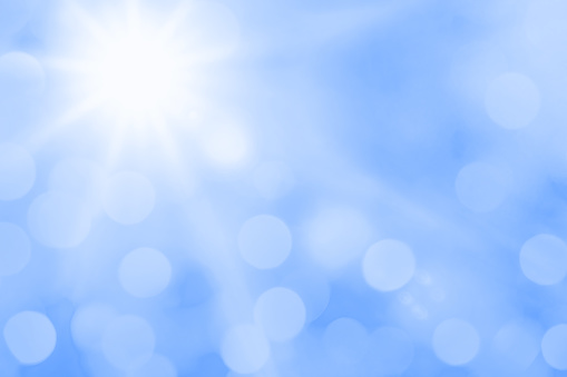Bright sun with beautiful beams and bokeh light in a blue sky. Space for copy.