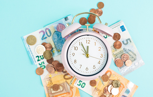 Alarm clock with Euro banknotes and coins, inflation, recession and financial crisis, high living costs