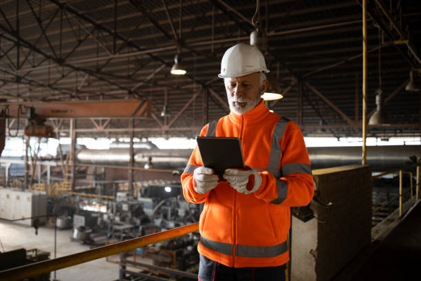 istock Industrial engineer worker wearing safety uniform and hardhat checking production on tablet computer. Factory interior. 1449159175