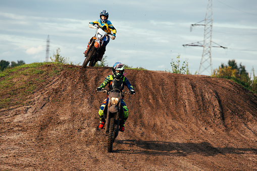 Racer boy on motorcycle participates in motocross race, active extreme sport, flying debris from a motocross in dirt track