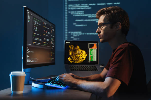 młody informatyk pracujący na komputerze w domu, debugujący błąd cyberprzestrzeni java script - python zdjęcia i obrazy z banku zdjęć