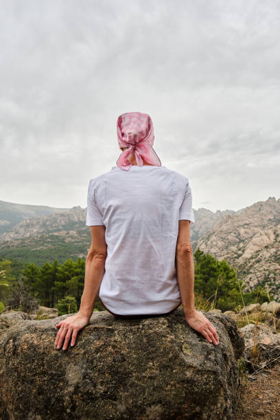 Rear view of a woman with cancer sitting in nature. stock photo
