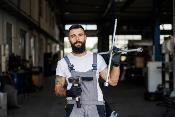Portrait of an auto mechanic holding tools and smiling at the camera. stock photo
