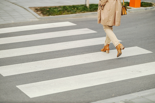 Female's legs crossing a street and walking on a crossroad.