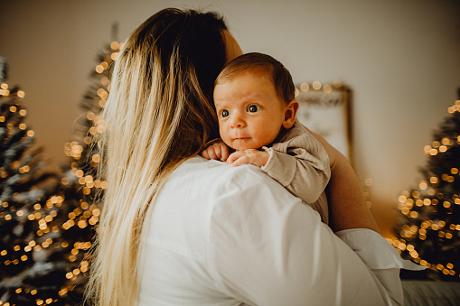 Portrait of a baby boy in his mother's arms at home.