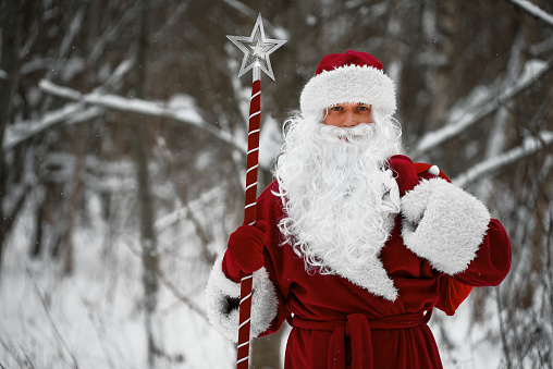 Santa Claus with magic staff and sack of Christmas gifts.