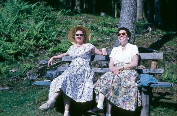 Meran, South Tyrol, Italy, 1956. Two women sitting on a bench in a forest clearing enjoy the spring sun.
