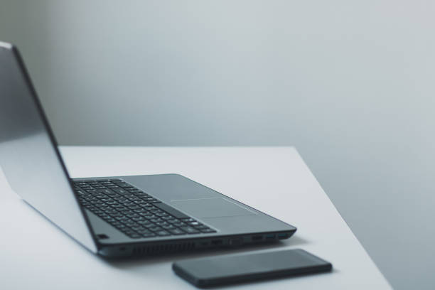istock Laptop computer with opened lid and smart phone on table in office workspace. 1449189391