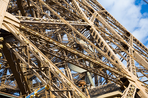 Architecture of Eiffel Tower. Closeup view of metal frames, beams, rivets against blue sky as background