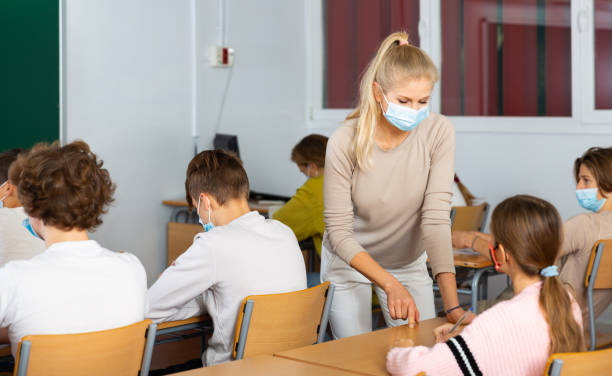 istock Teacher in mask explaining new theme to children 1449191513