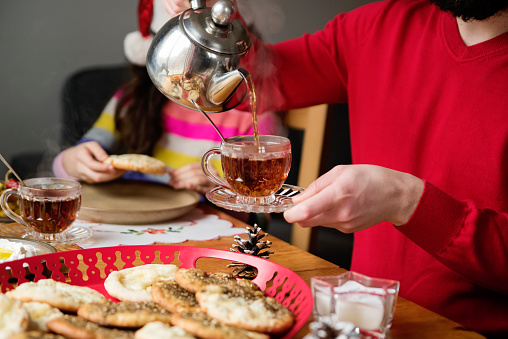 Middle eastern family having a festive breakfast. They are having tea and manakish, a traditional bread made with cheese and Zaatar. Little girl is wearing a festive Santa’s hat. Horizontal waist up indoors shot. This was taken in Montreal, Quebec, Canada.
