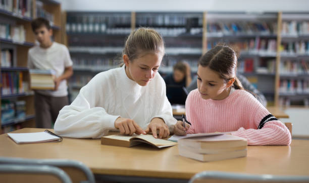 istock Girls doing homework together in library 1449192357