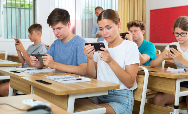 Girls and boys students using mobile phones during lecture
