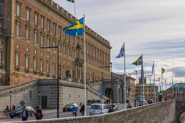 schöne aussicht auf schwedische nationalflaggen an der fassade des königspalastes und den hintergrund des bewölkten himmels. . - stadsholmen stock-fotos und bilder