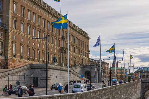 Sweden. Stockholm. 05.18.2022 Beautiful view of swedish national flags on The Royal Palace facade and cloudy sky background.