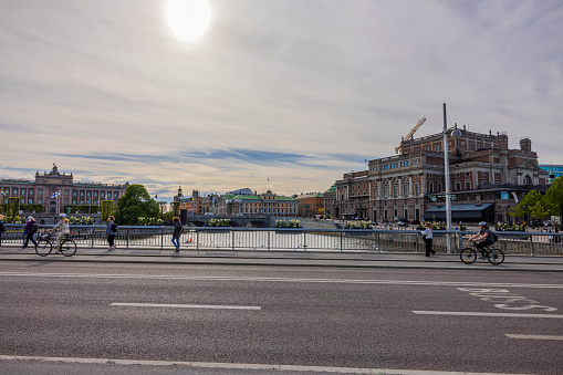 Stockholm. Sweden. Europe. 05.18.2022. Beautiful view of pedestrians and bicycles passing over bridge and old historical buildings on cloudy sky background.