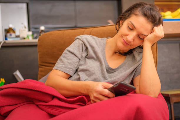istock Woman using cell phone on sofa in living room 1449195229