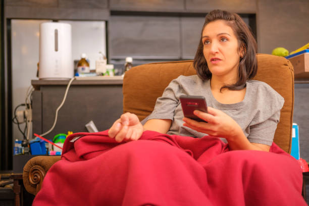 istock Woman using cell phone on sofa in living room 1449195341