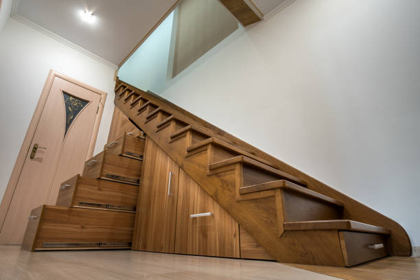 istock Modern architecture interior with luxury hallway with glossy wooden stairs in multi-storey house. Custom built pullout cabinets on glides in slots under stairs. Use of space for storage. 1449198415