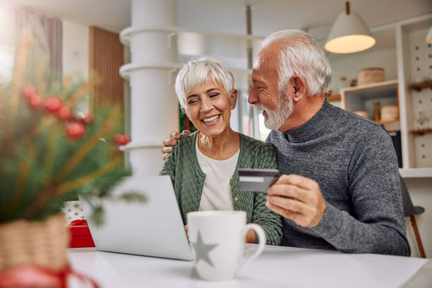 an embracing elderly couple shopping online for Christmas stock photo