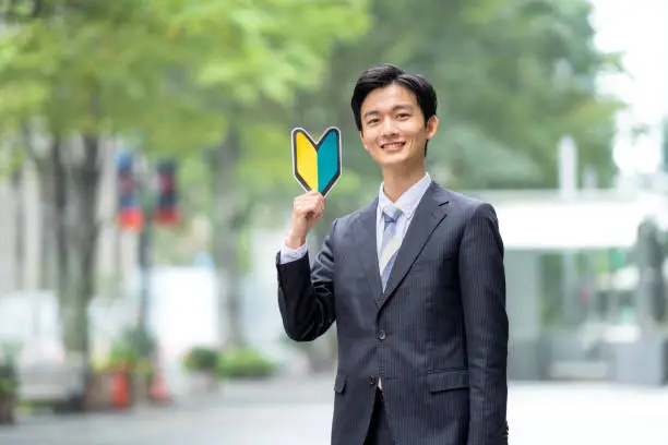 A Japanese man in a suit with a beginner's mark