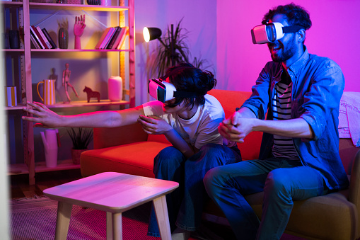 Portrait of a young couple having fun with virtual reality headsets at home