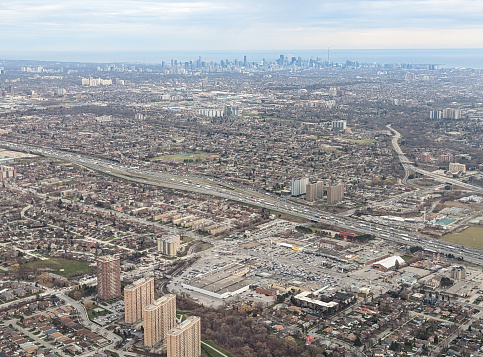 King's Highway 401 spans part of southern Ontario in one of the busiest highway networks in North America. High angle view to the southeast with downtown Toronto and Lake Ontario in the background.  Autumn afternoon.