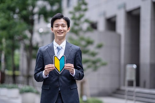 A Japanese man in a suit with a beginner's mark