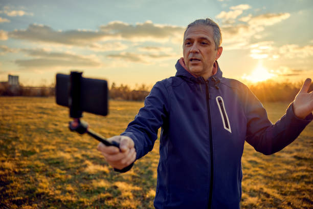 istock Social media influencer creating content. Man shooting video of himself using cellphone. 1449217229
