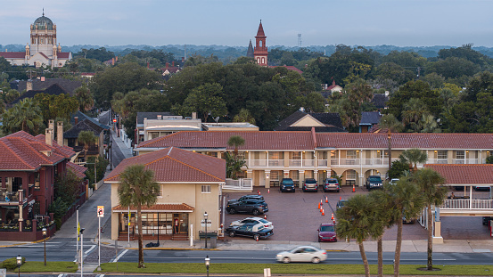Hotel with parking lot in  Saint Augustine with the Flager Memorial Presbyterian Church and Cathedral Basilica of St. Augustine visible at the distance.