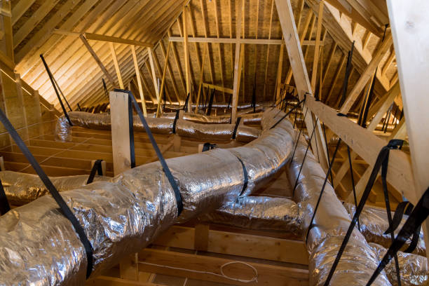 In a newly built home under construction, ventilation pipes are found in the silver insulation material on the ceiling of the attic stock photo