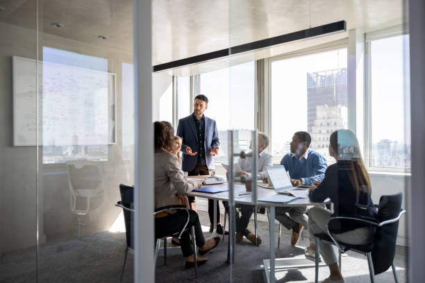 hombre de negocios exitoso hablando con un grupo de personas en una reunión en la oficina - meeting fotografías e imágenes de stock