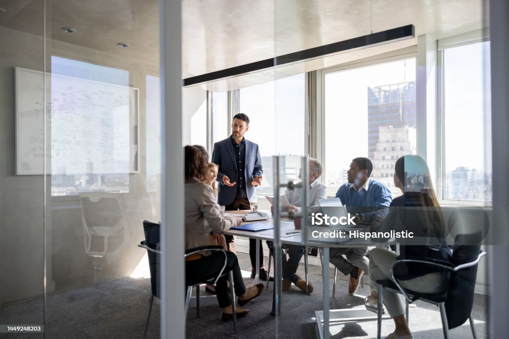 Successful business man talking to a group of people in a meeting a the office Successful Latin American business man talking to a group of people in a meeting a the office Meeting Stock Photo