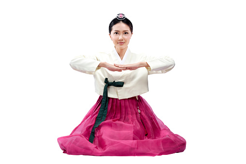 Asian woman wearing a traditional Korean national costume, Hanbok, sitting isolated over white background